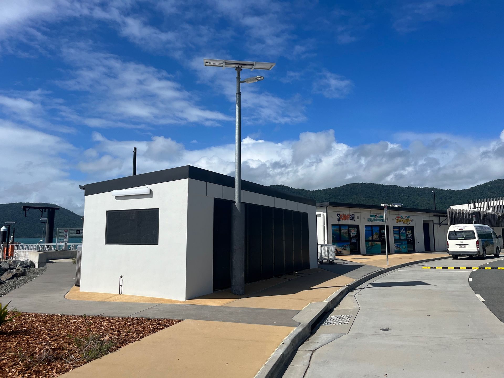 White Building and Shops on a Sunny Waterfront, With a Solar Street Light — Red Emperor Constructions in Cannonvale, QLD