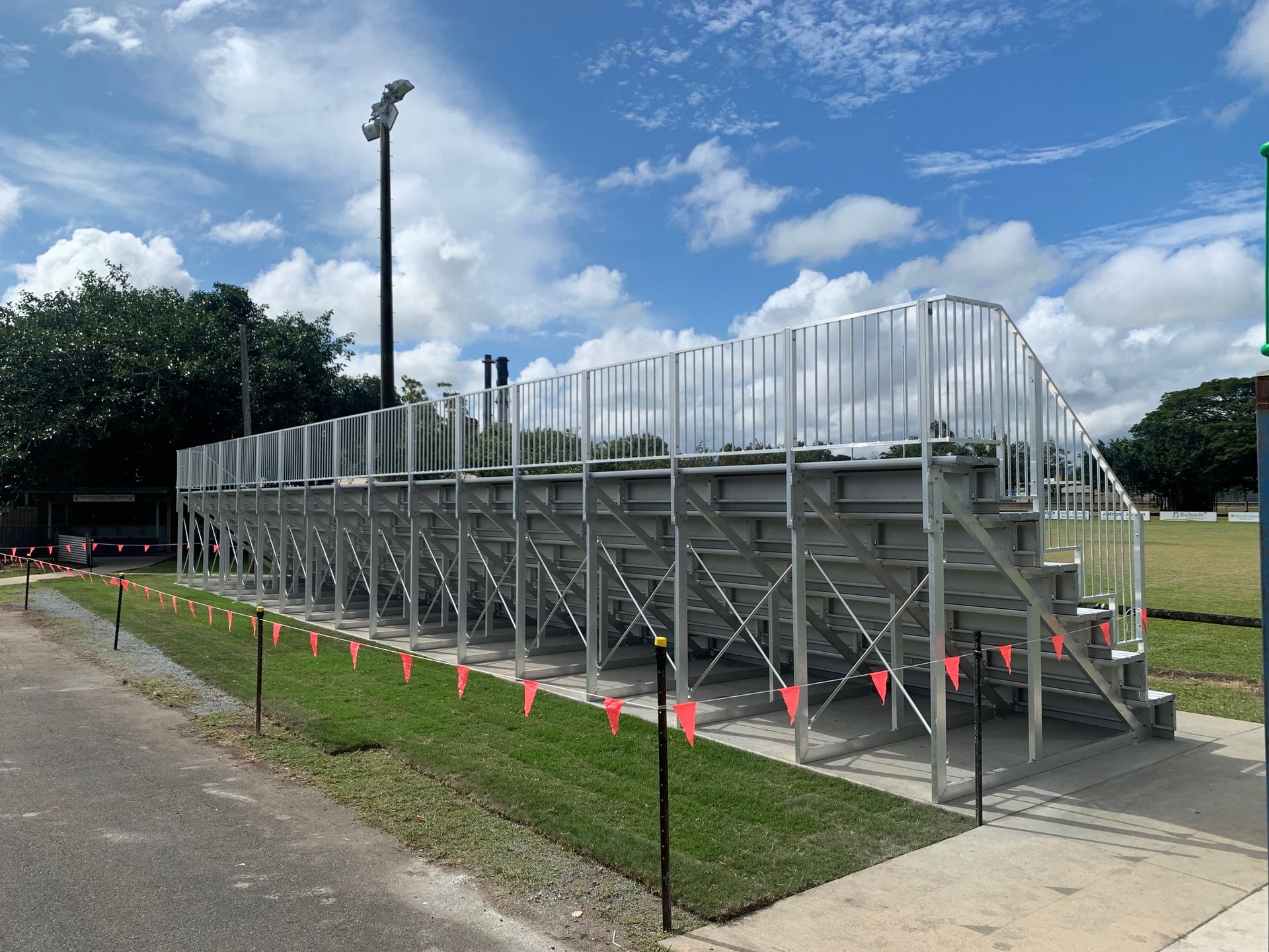 A bleacher is sitting on the side of the road next to a grassy field — Red Emperor Constructions in Cannonvale, QLD