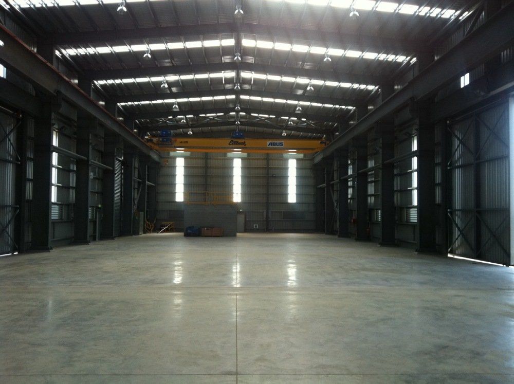 A large empty warehouse with a crane in the background — Red Emperor Constructions in Cannonvale, QLD