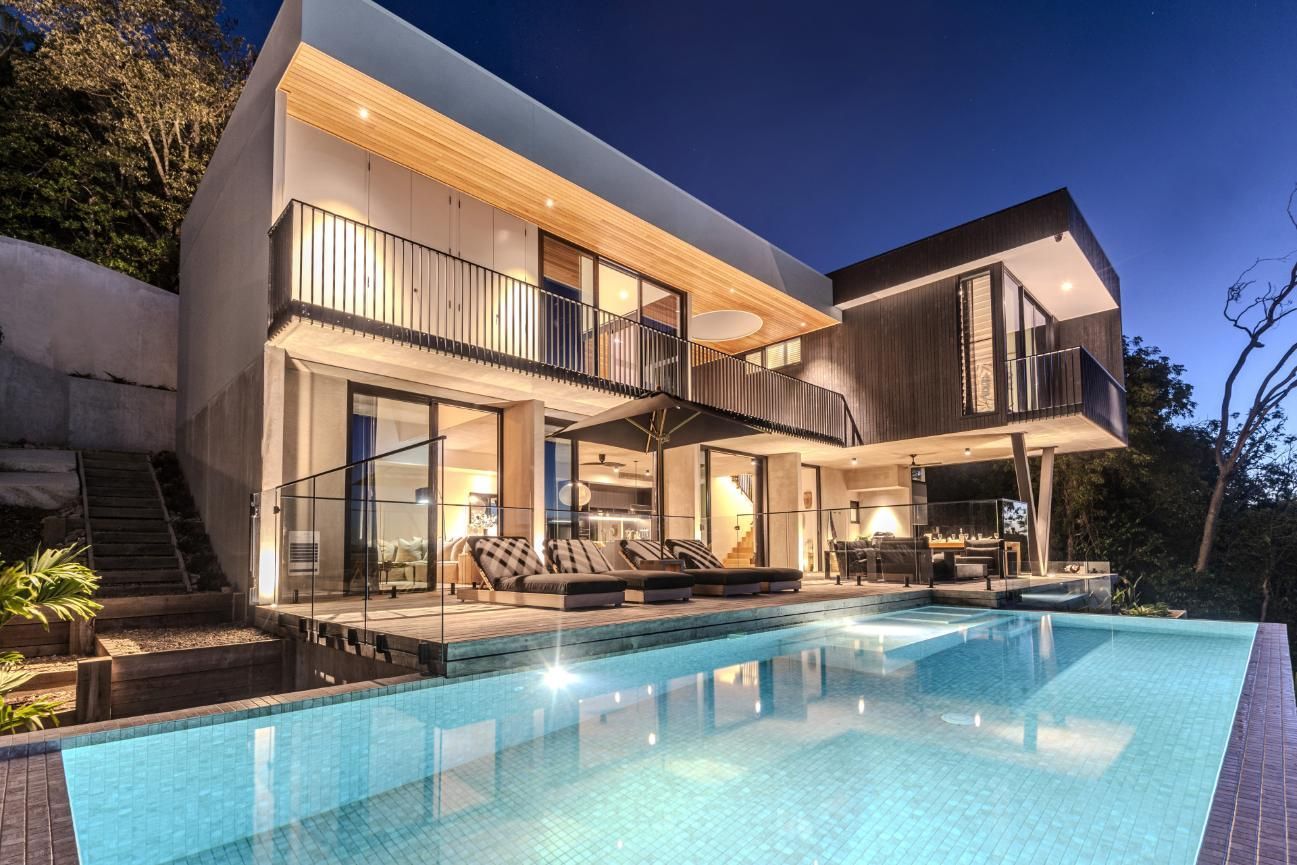 Modern House at Night With Pool and Pool Lights Reflecting in Water — Red Emperor Constructions in Cannonvale, QLD