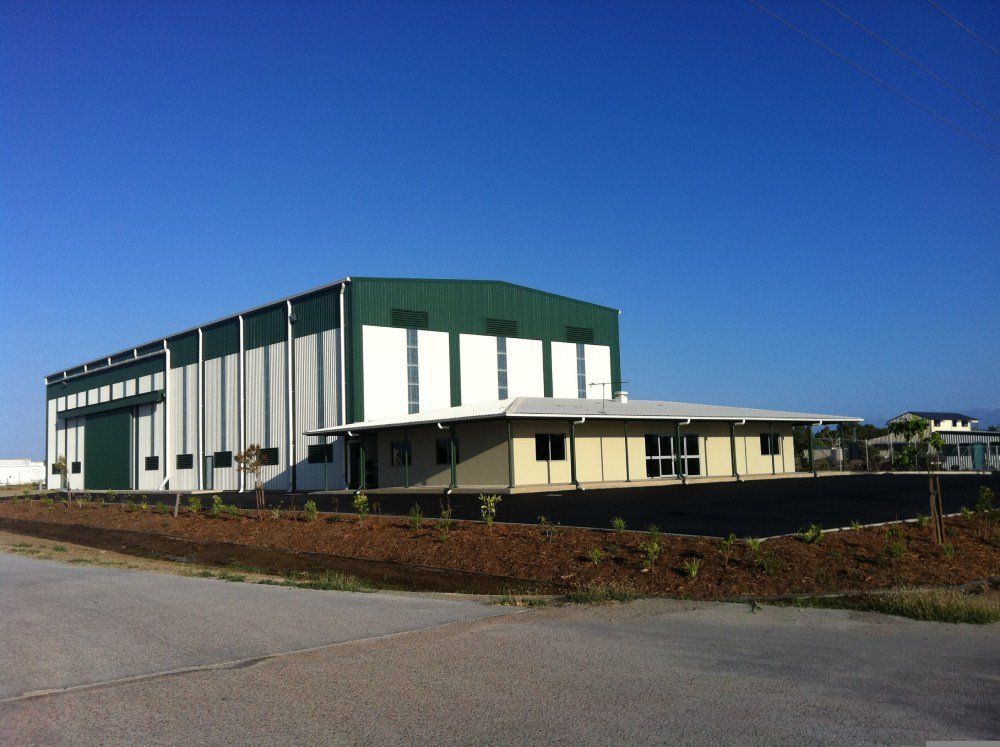 A Green and White Building With a Blue Sky in the Background — Red Emperor Constructions in Cannonvale, QLD