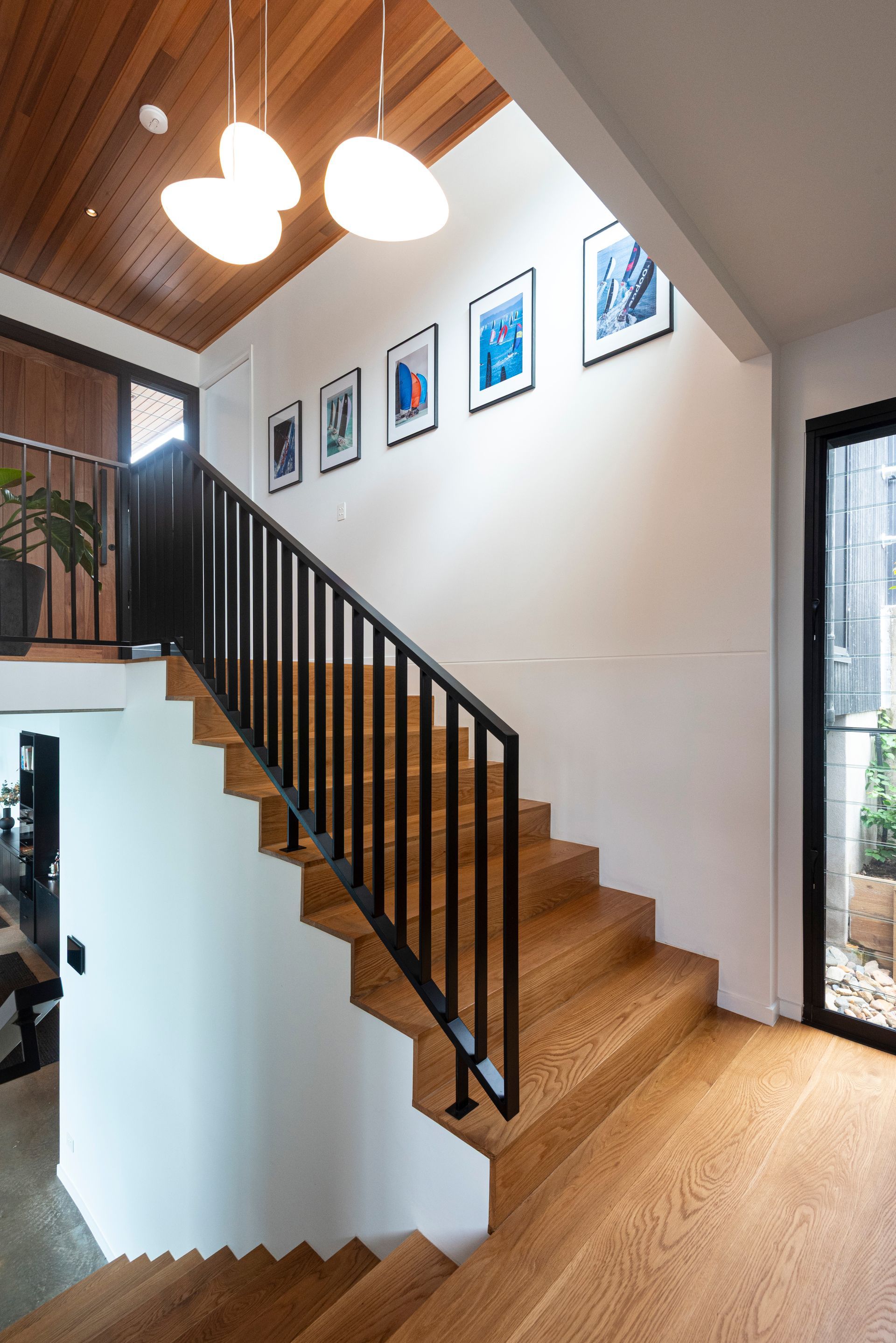 Staircase With Wooden Steps, Black Railing and Framed Artwork — Red Emperor Constructions in Cannonvale, QLD