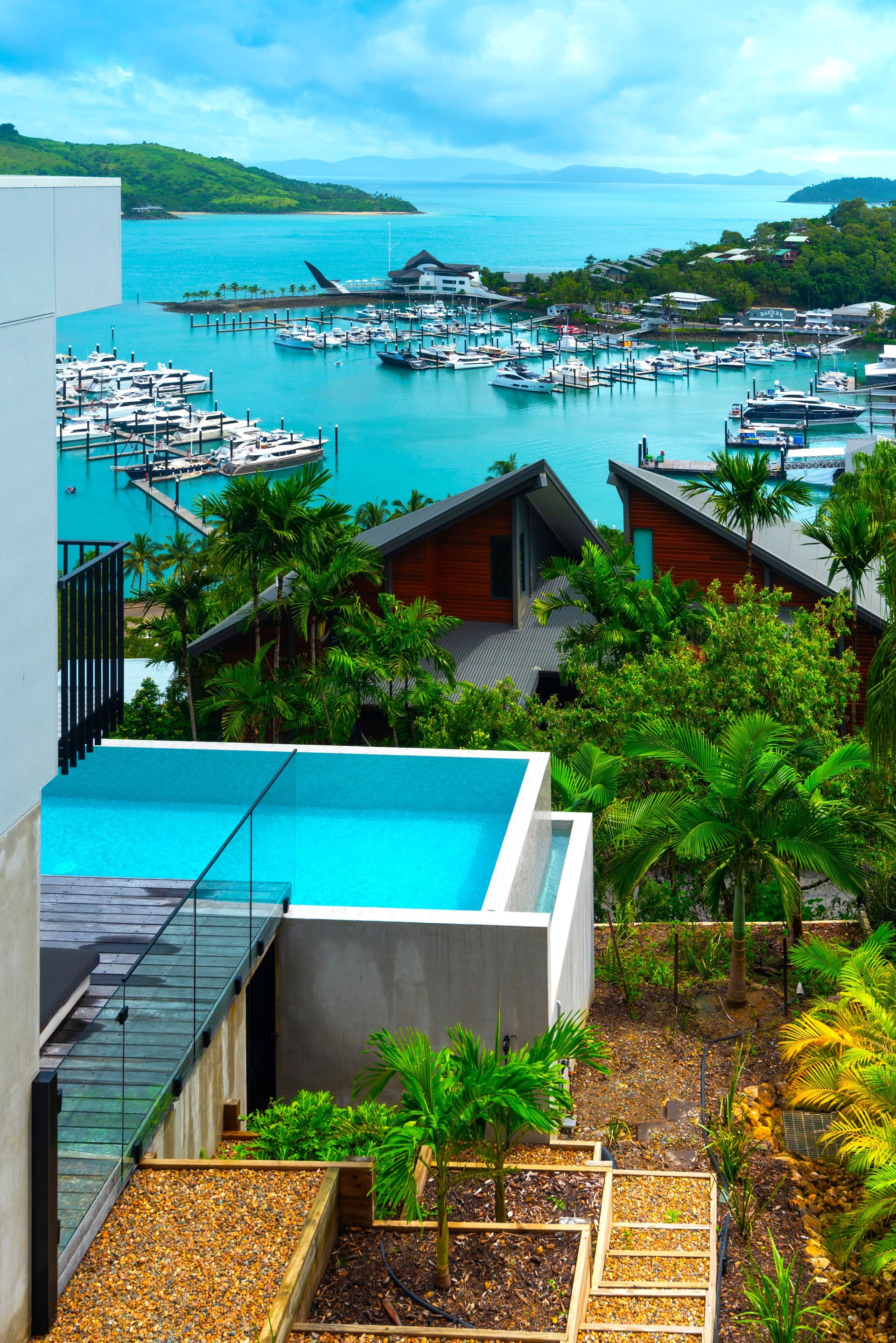 Overlooking a Marina, a House With a Blue-tiled Pool and Tropical Foliage — Red Emperor Constructions in Cannonvale, QLD