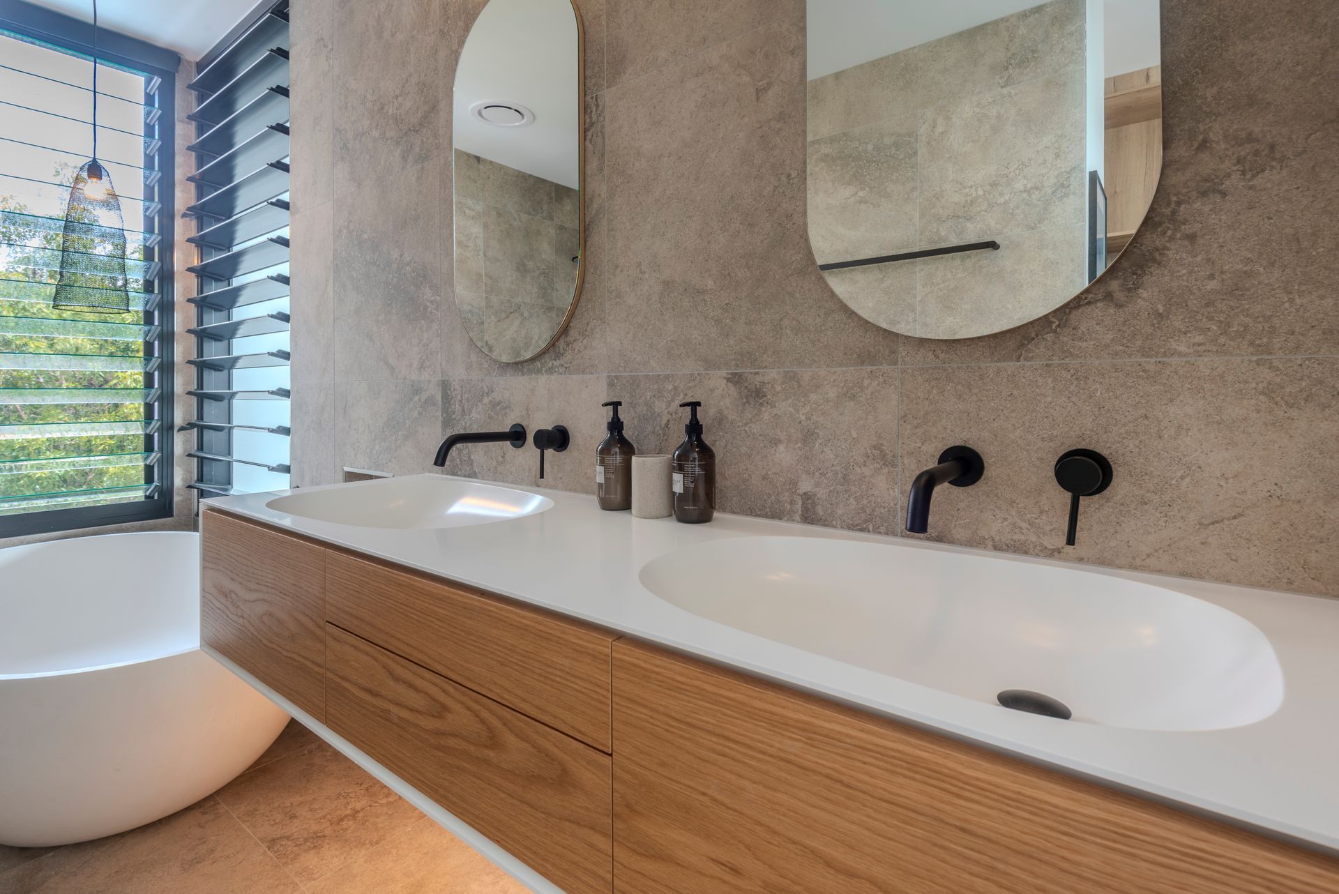 Modern Bathroom With Dual Sinks, Oval Mirrors, Wood Cabinetry — Red Emperor Constructions in Cannonvale, QLD