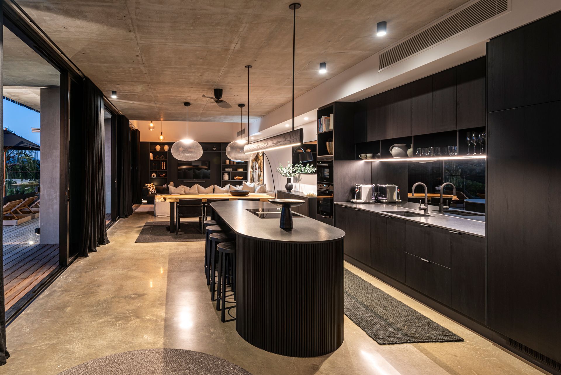 Modern Kitchen With Dark Cabinetry, Island, and Concrete Floor — Red Emperor Constructions in Cannonvale, QLD