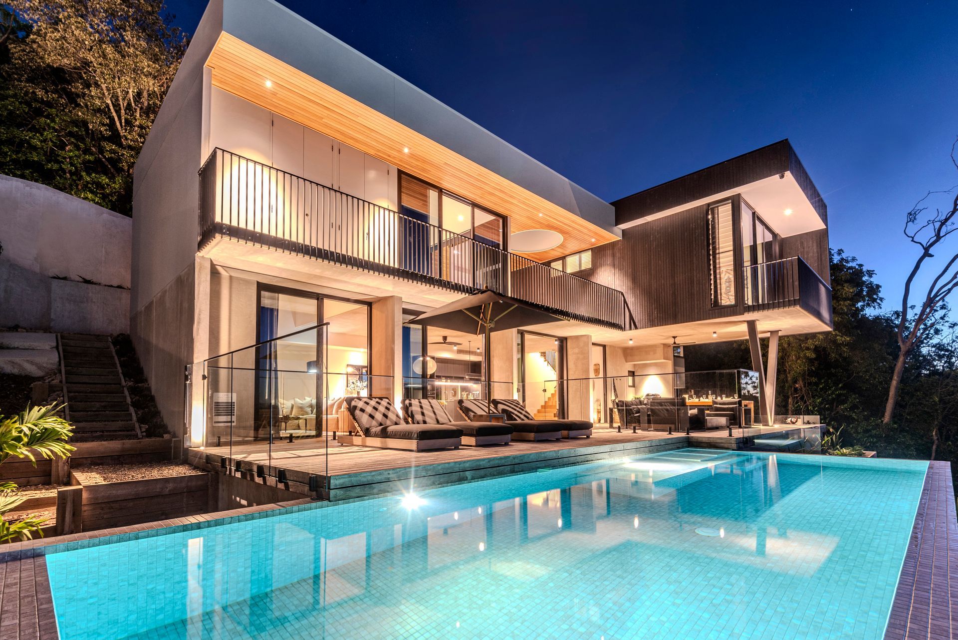 Modern Villa at Dusk With Pool, Outdoor Seating, and Balconies — Red Emperor Constructions in Cannonvale, QLD