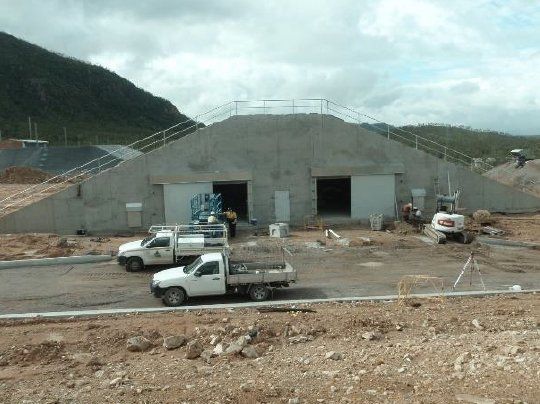 Two white trucks are parked in front of a building under construction — Red Emperor Constructions in Cannonvale, QLD