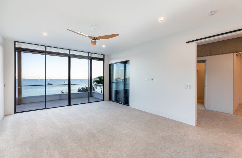 An empty room with a ceiling fan and a view of the ocean — Red Emperor Constructions in Cannonvale, QLD