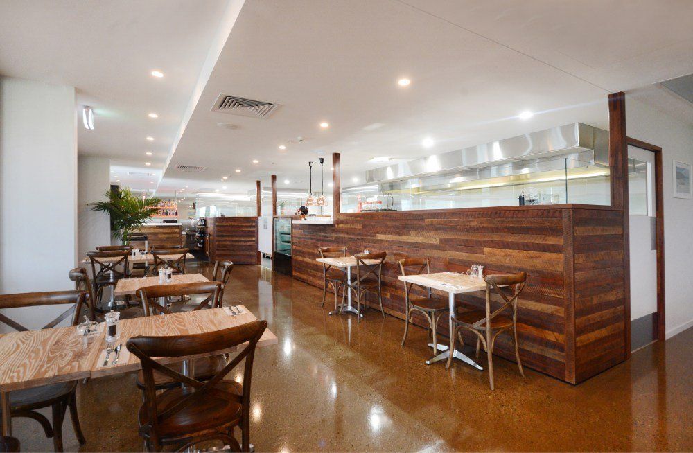 A restaurant with tables and chairs and a wooden wall — Red Emperor Constructions in Cannonvale, QLD