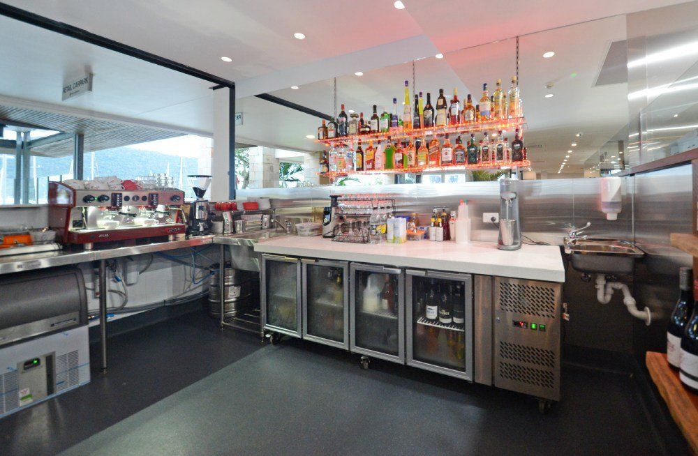 A kitchen with a lot of stainless steel appliances and a bar — Red Emperor Constructions in Cannonvale, QLD