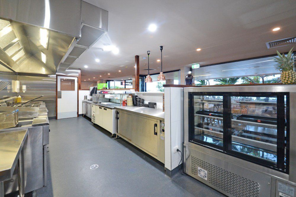 A kitchen with a lot of stainless steel appliances and a refrigerator — Red Emperor Constructions in Cannonvale, QLD
