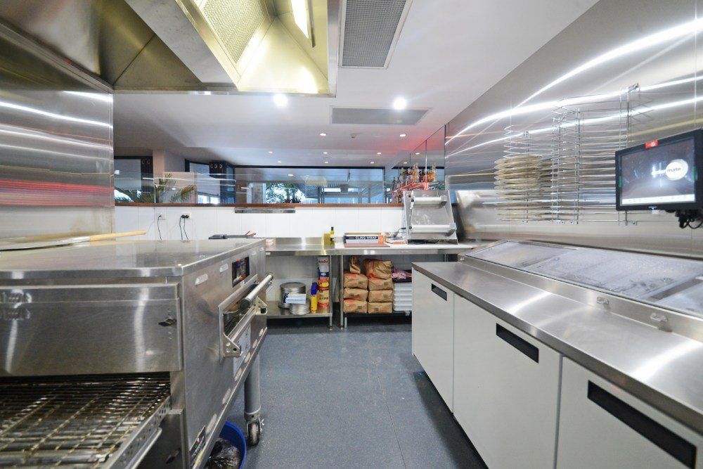 A Kitchen With Stainless Steel Appliances and a Tv on the Wall — Red Emperor Constructions in Cannonvale, QLD