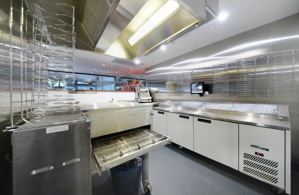 A kitchen with stainless steel appliances and a conveyor belt — Red Emperor Constructions in Cannonvale, QLD