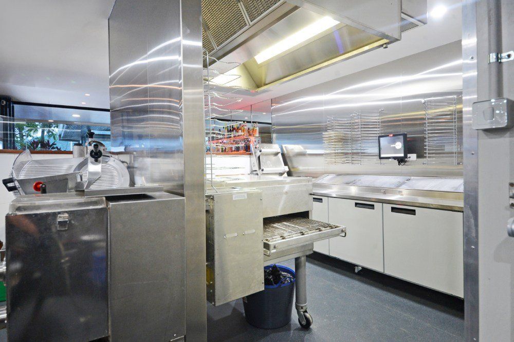 A kitchen with stainless steel appliances and a pizza oven — Red Emperor Constructions in Cannonvale, QLD