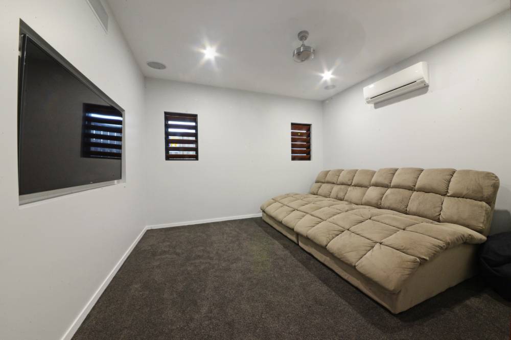 A living room with a large couch and a flat screen tv — Red Emperor Constructions in Cannonvale, QLD