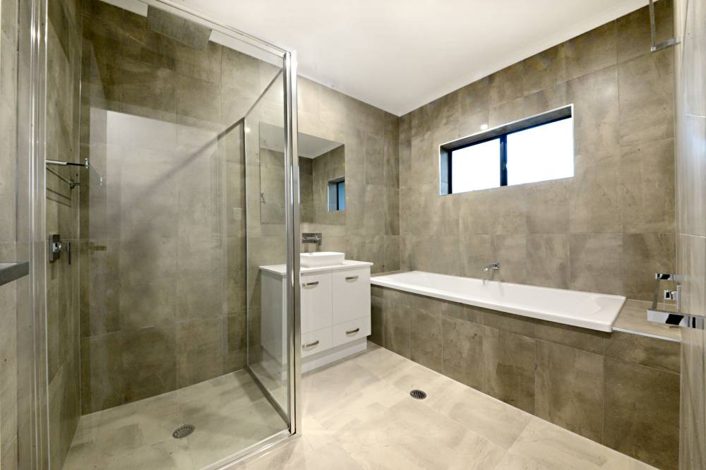 A bathroom with a tub , sink , shower and mirror — Red Emperor Constructions in Cannonvale, QLD