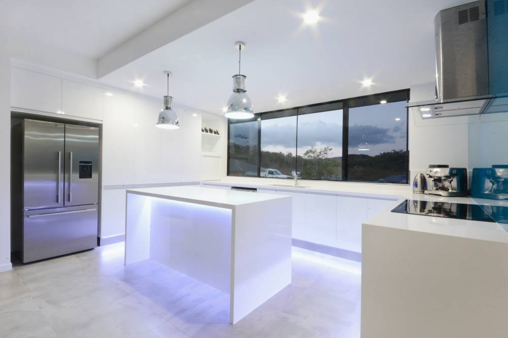 A kitchen with a large island and a stainless steel refrigerator — Red Emperor Constructions in Cannonvale, QLD