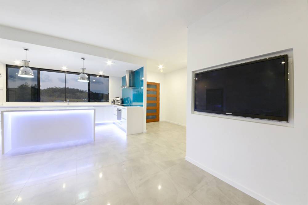A kitchen with a large flat screen tv mounted on the wall — Red Emperor Constructions in Cannonvale, QLD