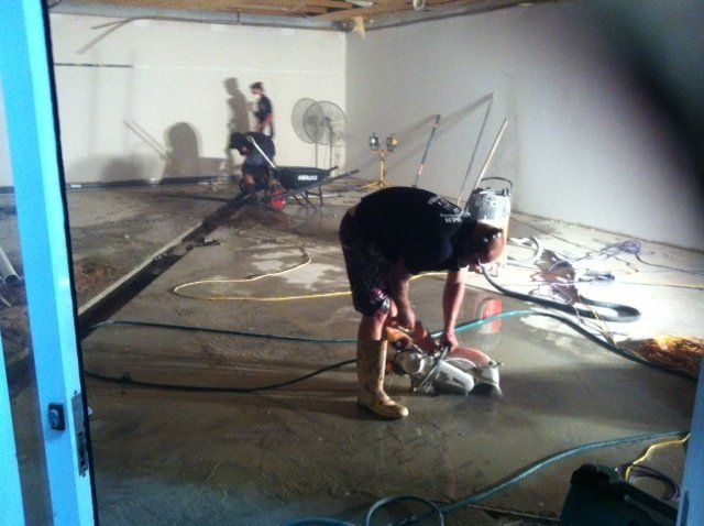 A man is working on a concrete floor in a room — Red Emperor Constructions in Cannonvale, QLD
