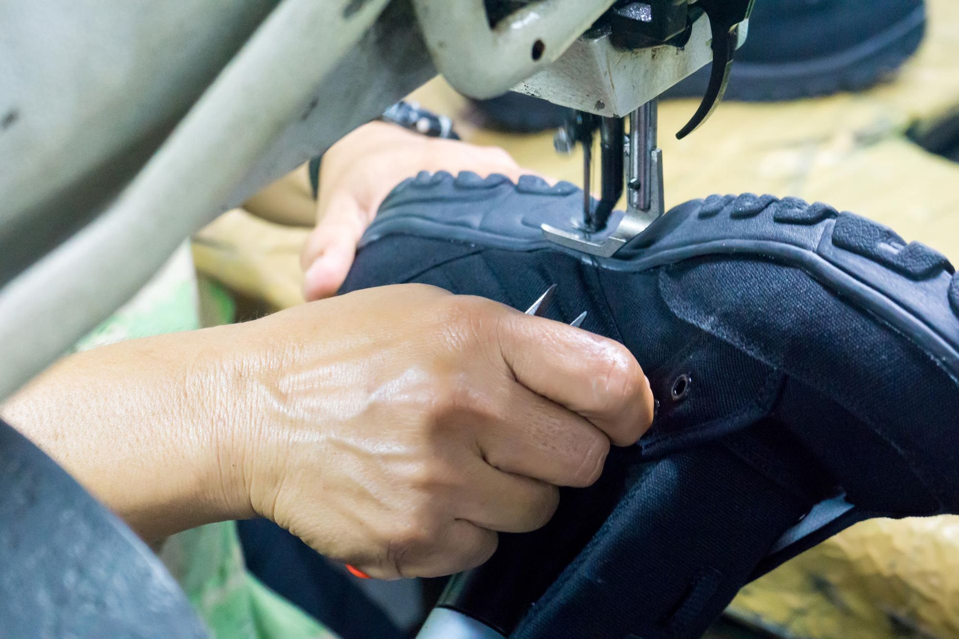 A person is sewing a shoe with a machine.