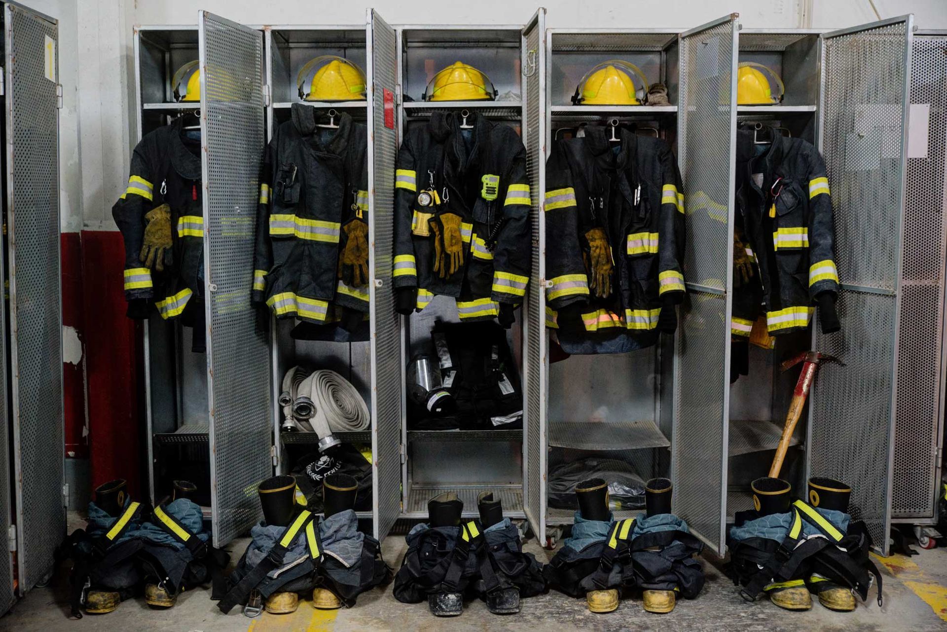 A row of lockers filled with firefighter 's uniforms and helmets