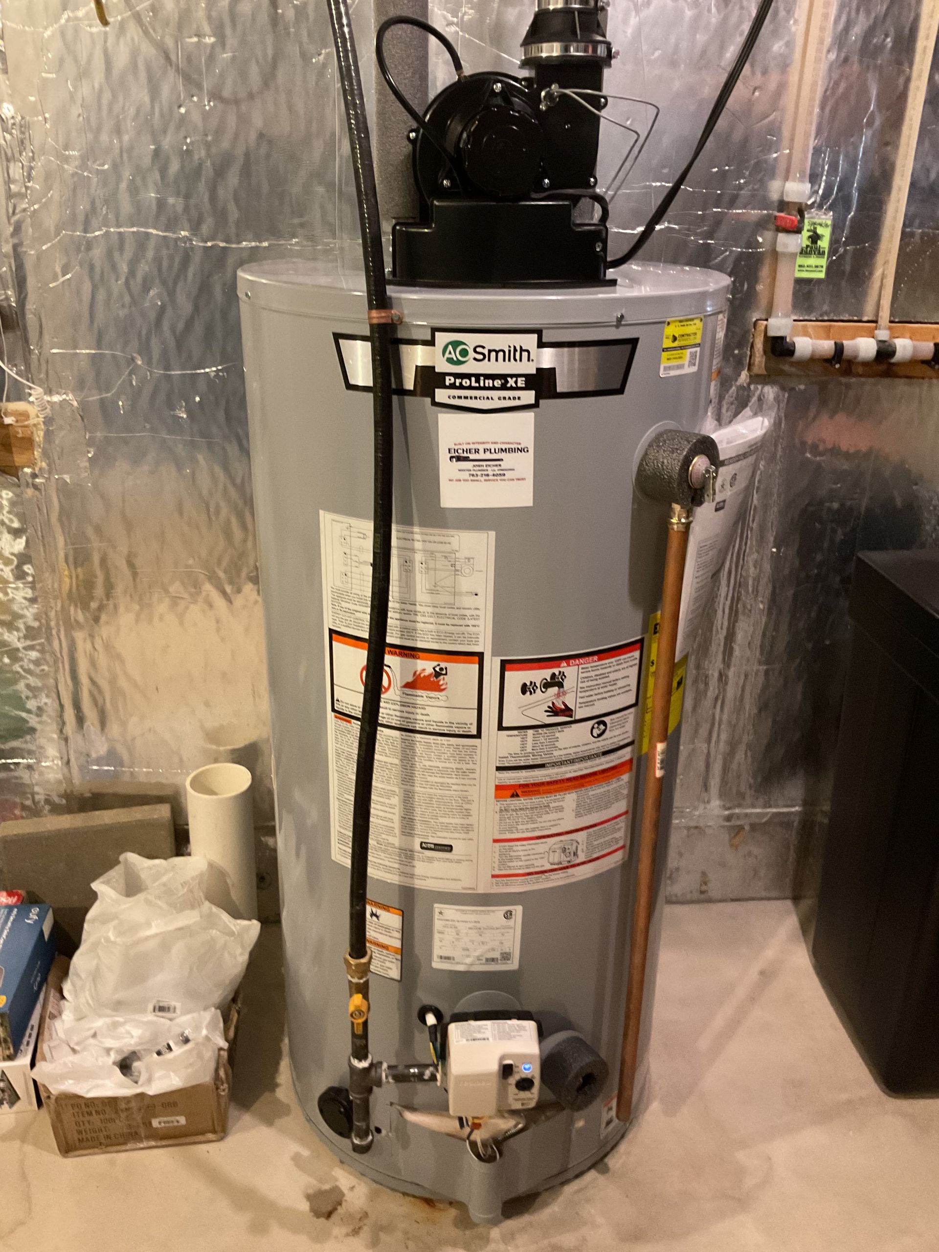Water heater in a utility room with insulated walls and plumbing pipes.