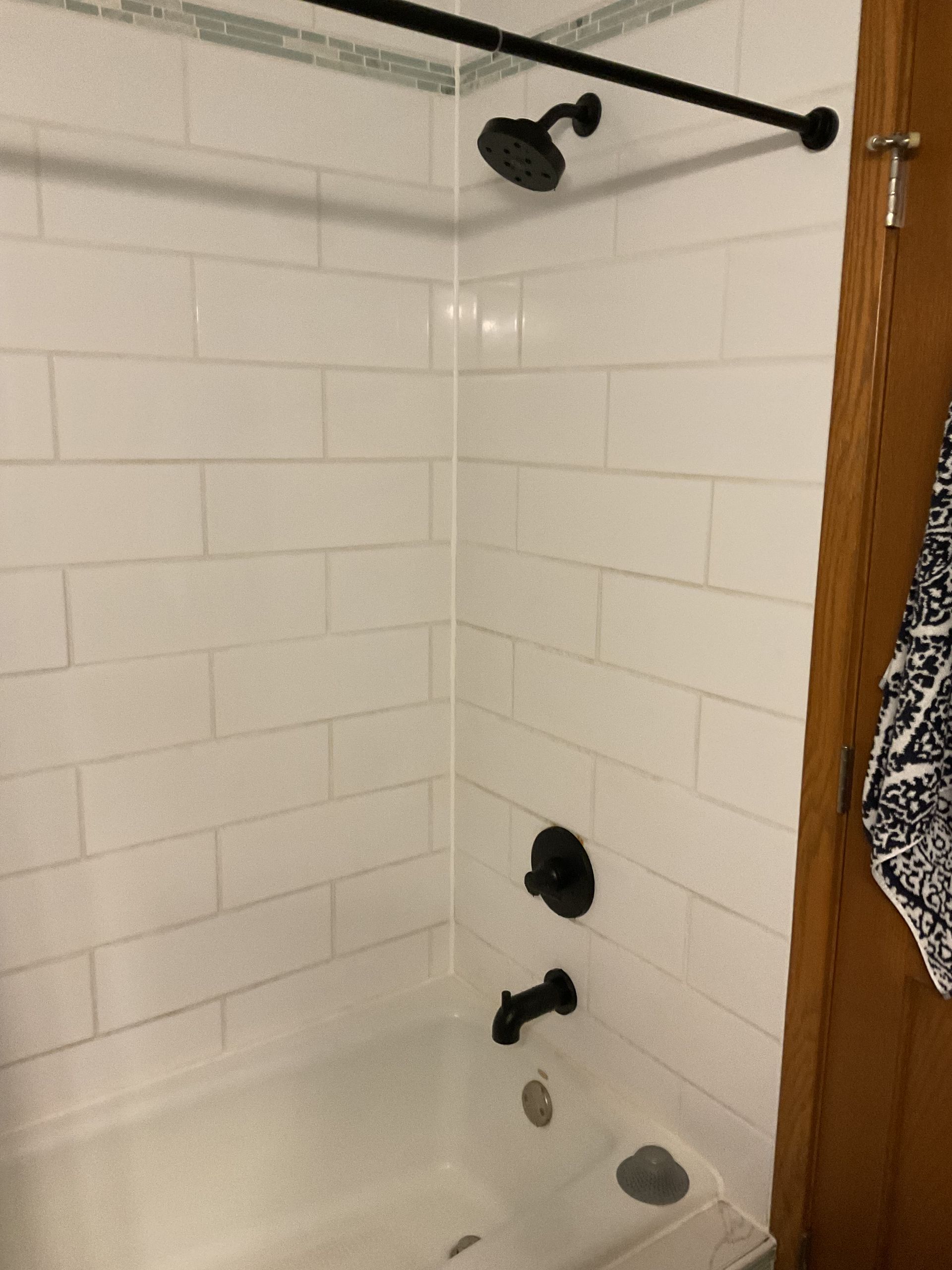 Empty bathtub with surround in a bathroom under construction, showing exposed ceiling framing above.
