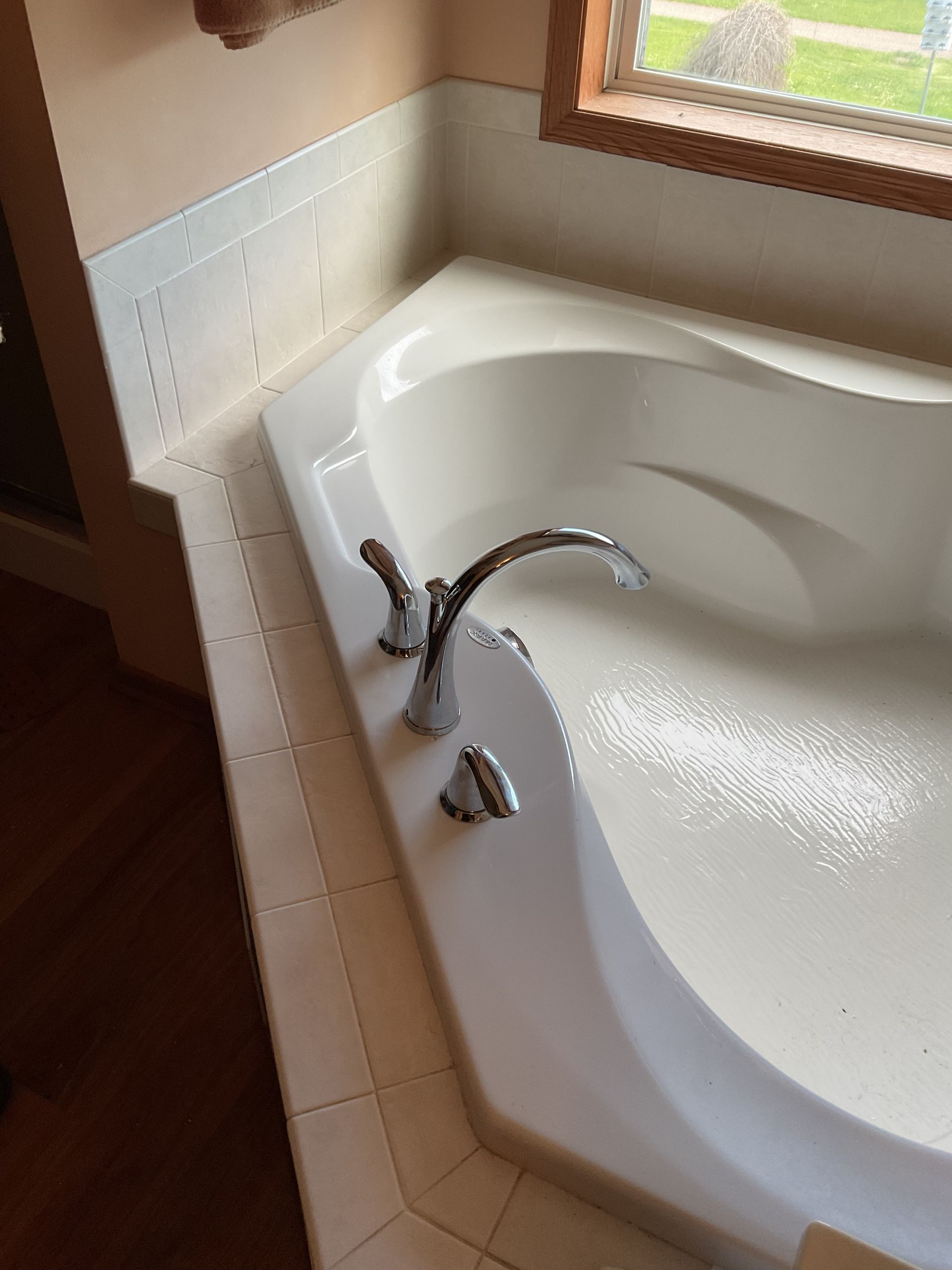 Small bathroom with bathtub, toilet, and dark wood vanity beside a mirror.