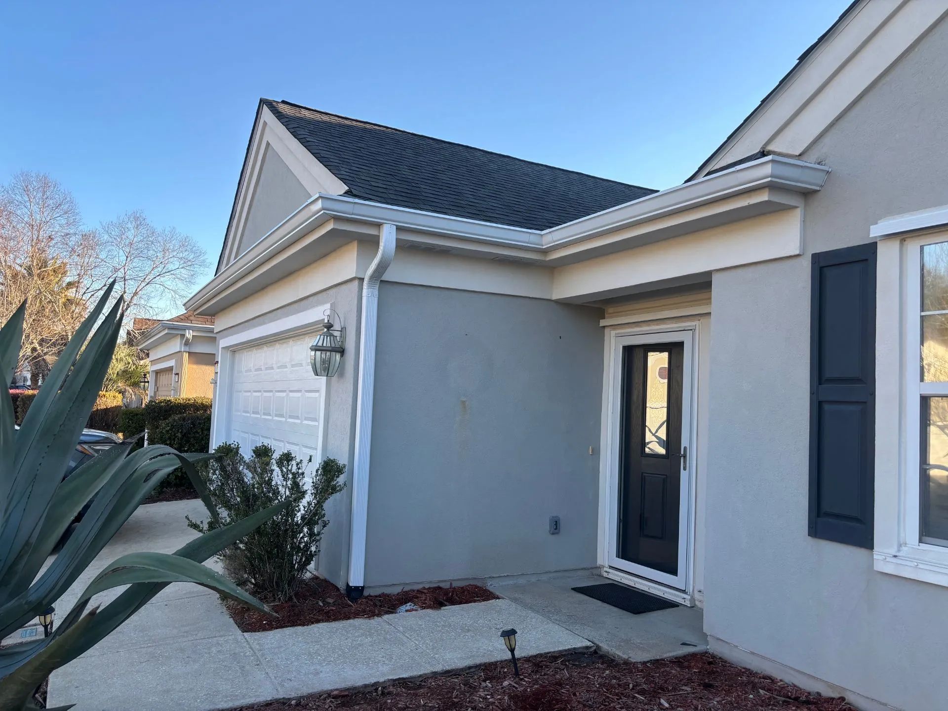 Modern gray house exterior with a front entry, white trim, and desert landscaping