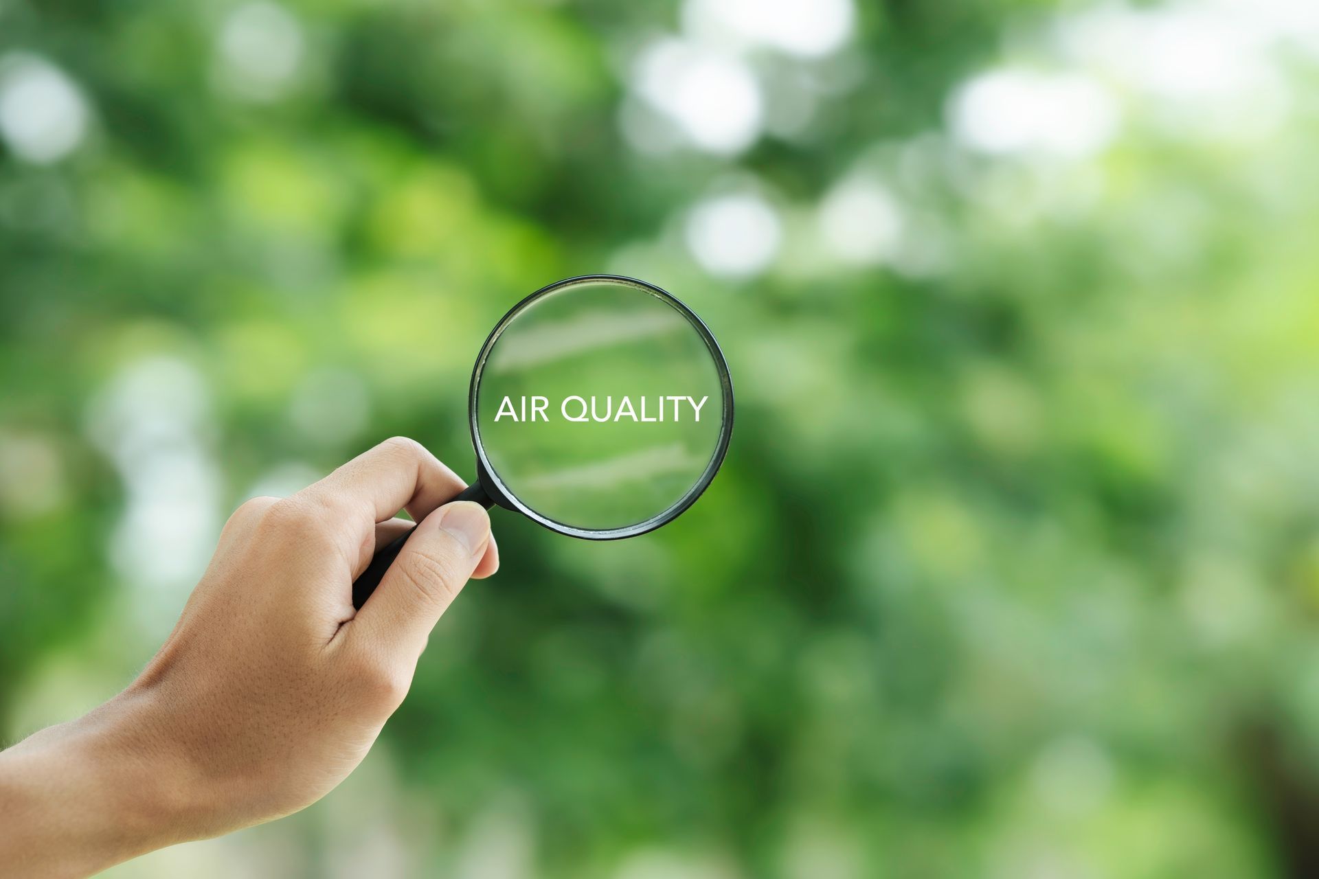 A person is holding a magnifying glass with the word air quality written on it.