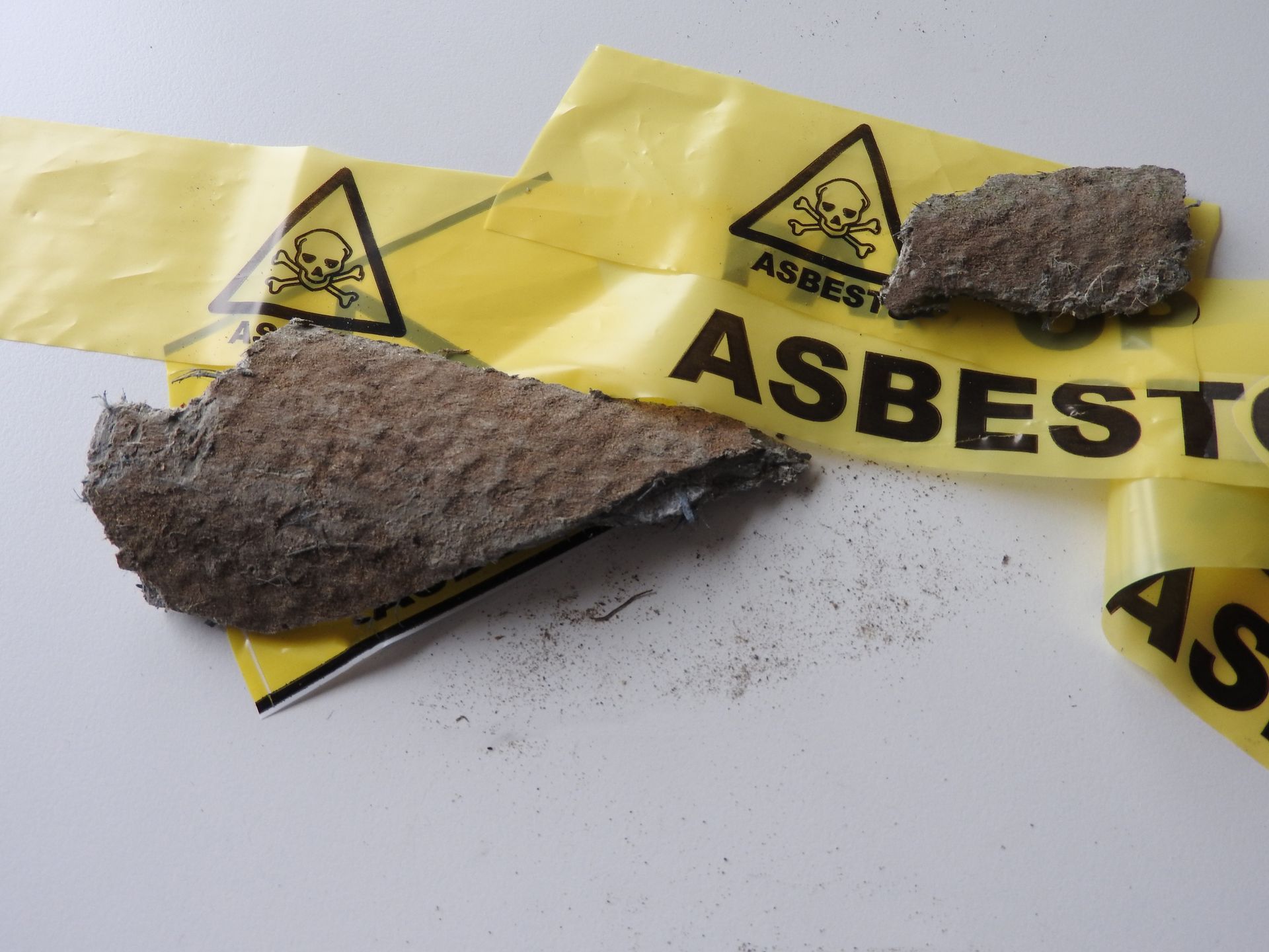 A piece of asbestos is laying on top of a yellow asbestos bag