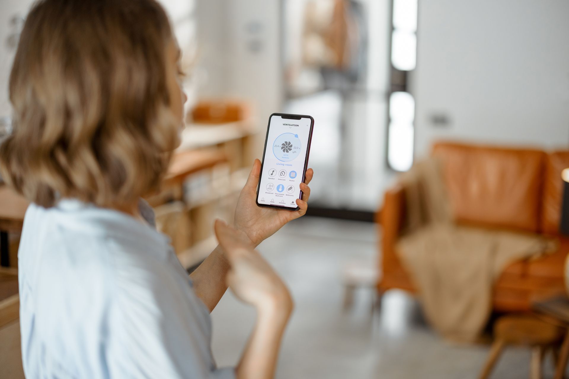 A woman is holding a smart phone in her hand in a living room.