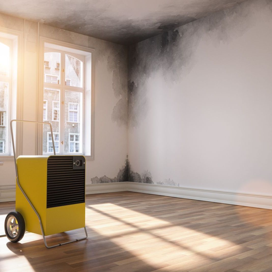 A yellow humidifier is sitting in an empty room next to a window.
