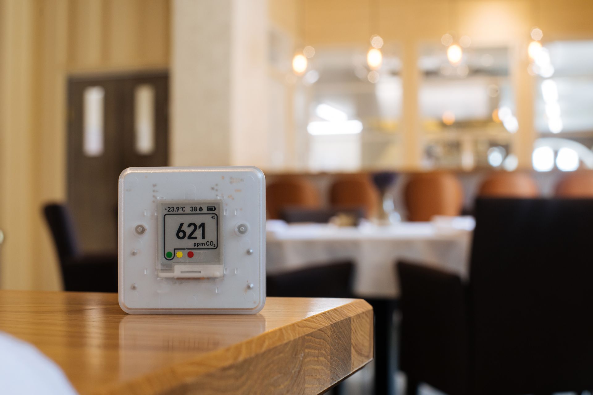 A thermostat is sitting on a wooden table in a restaurant.