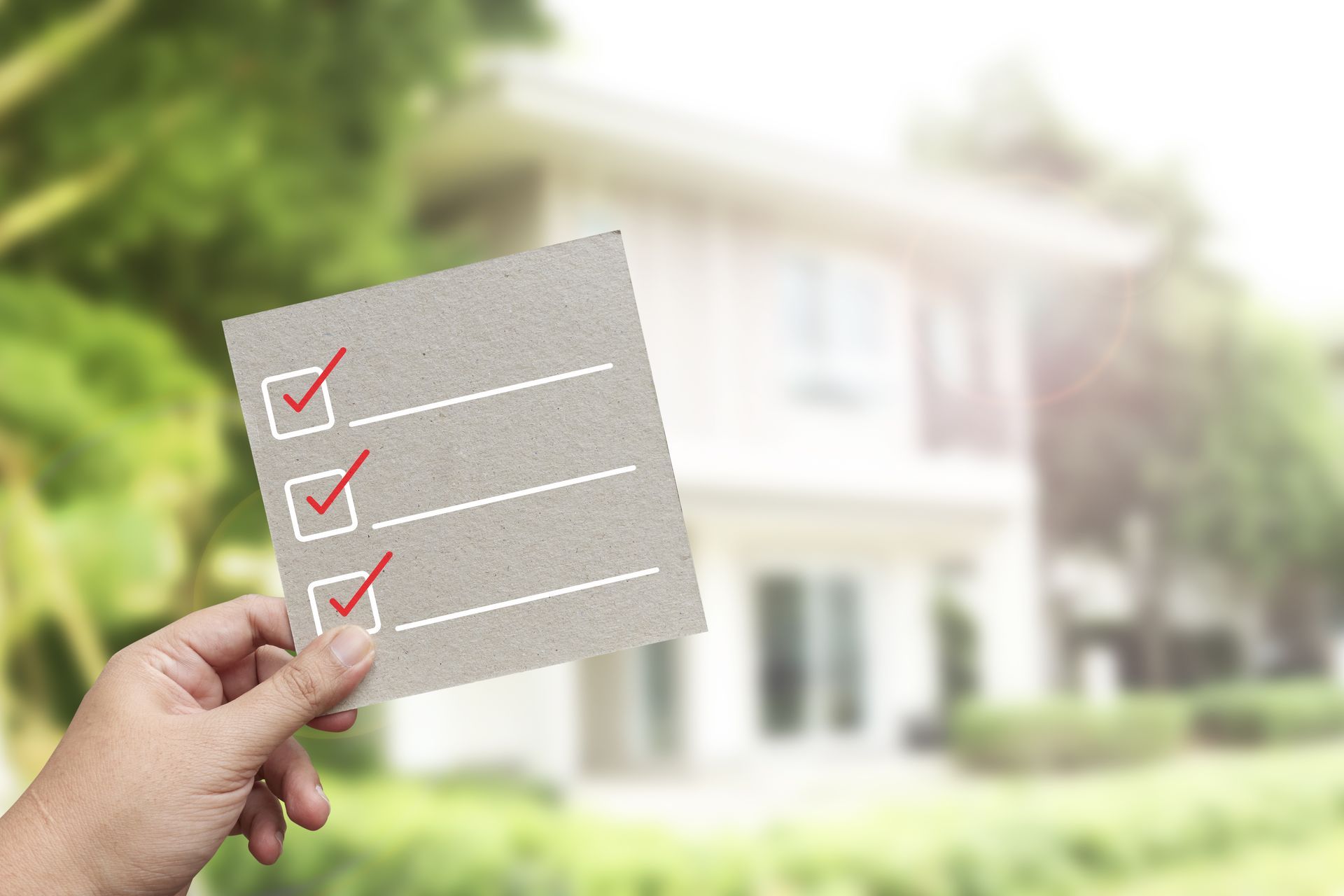 A person is holding a checklist in front of a house.