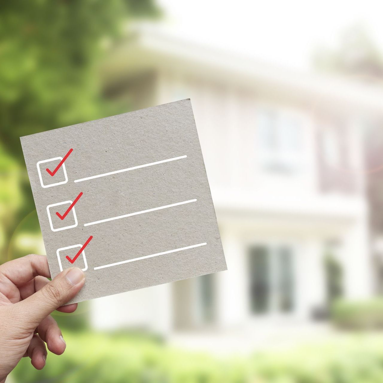 A person is holding a checklist in front of a house.