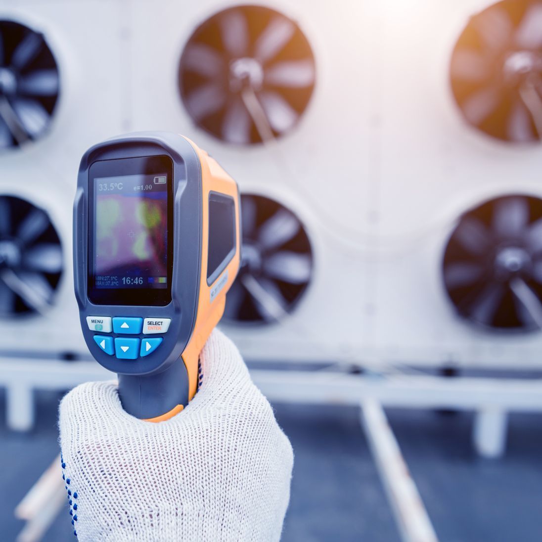 A person is holding a thermometer in front of a bunch of fans.