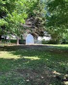 There is a shed in the middle of a park surrounded by trees.