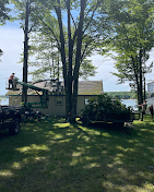 A man is cutting a tree in front of a house.