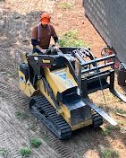 A man is riding a bulldozer on a dirt road.