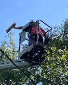 A man is standing in a bucket on top of a crane.