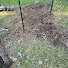 A pile of dirt is sitting on top of a lush green field.