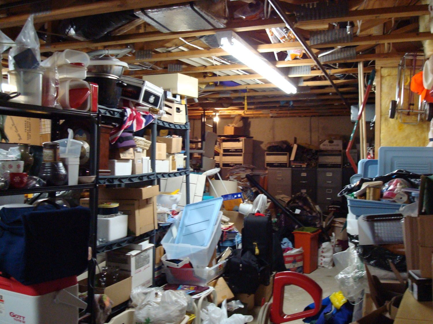 A cluttered basement with boxes and shelves including one that says ' jvc ' on it