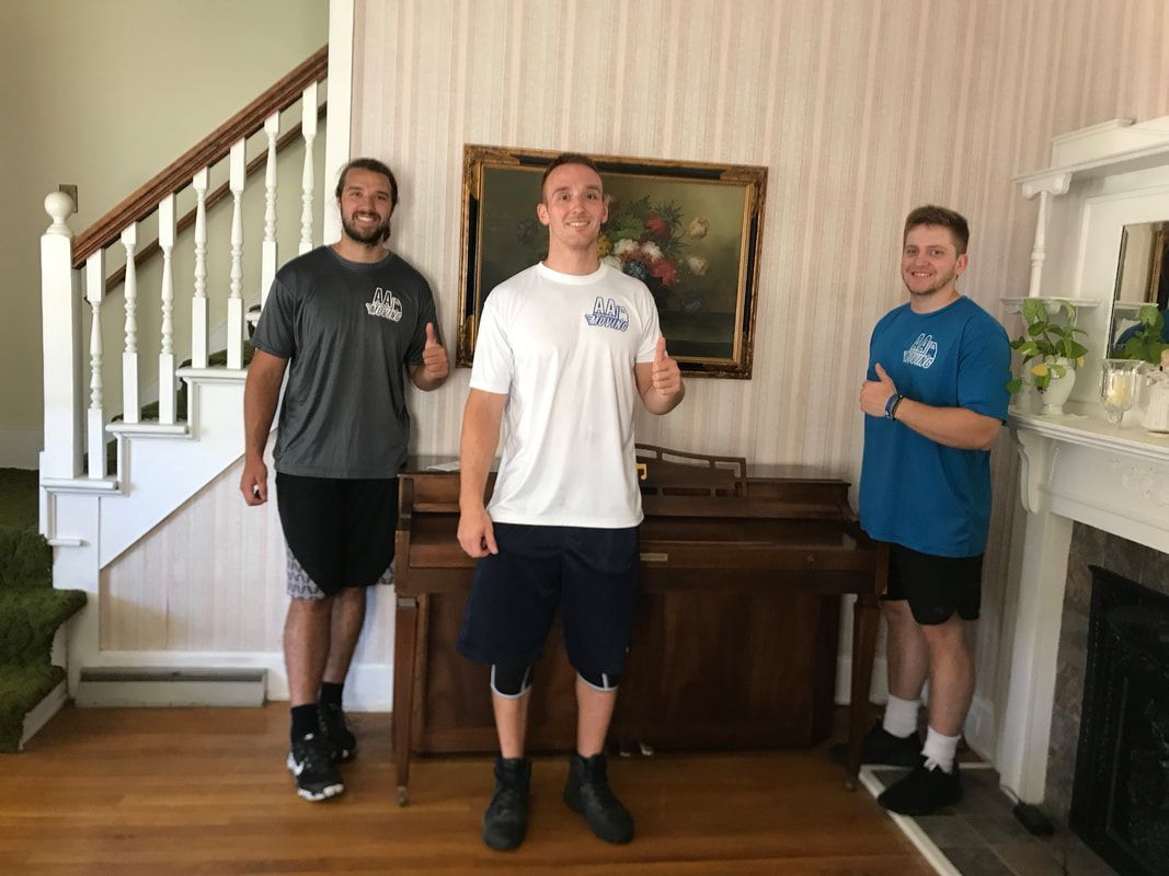 Three men are standing in a living room giving a thumbs up.