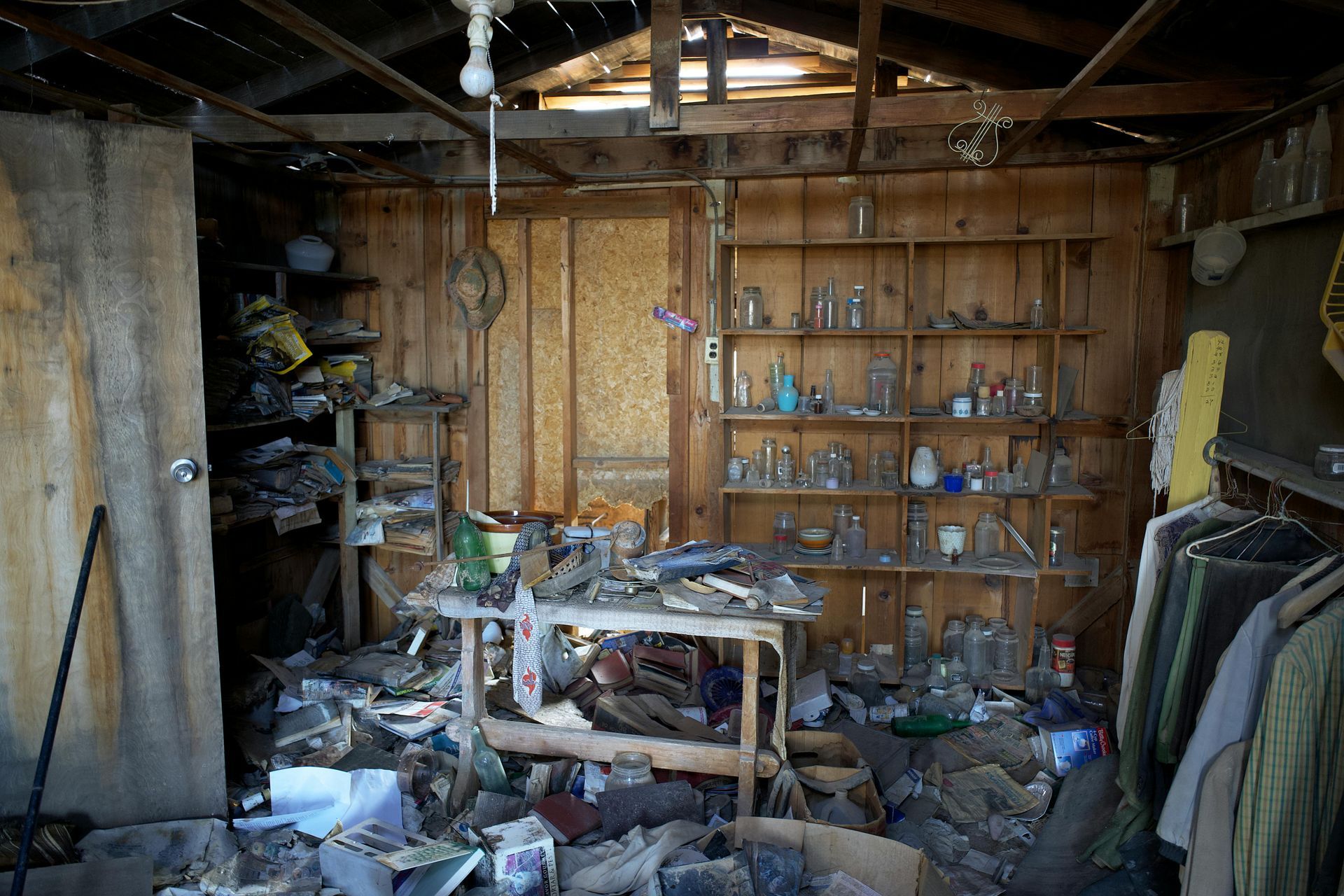 A messy room with a table and shelves full of bottles