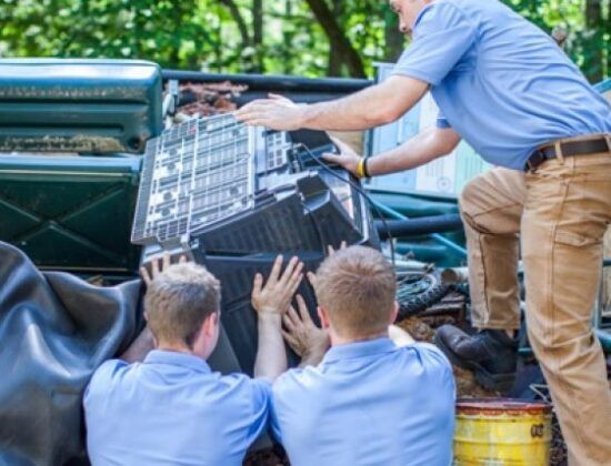 A group of men are loading a television into a truck.