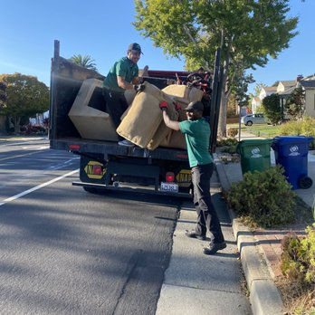 A man in a green shirt is loading boxes into a truck that says ym on the back