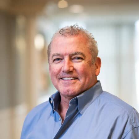 Man in blue shirt smiles, indoors.