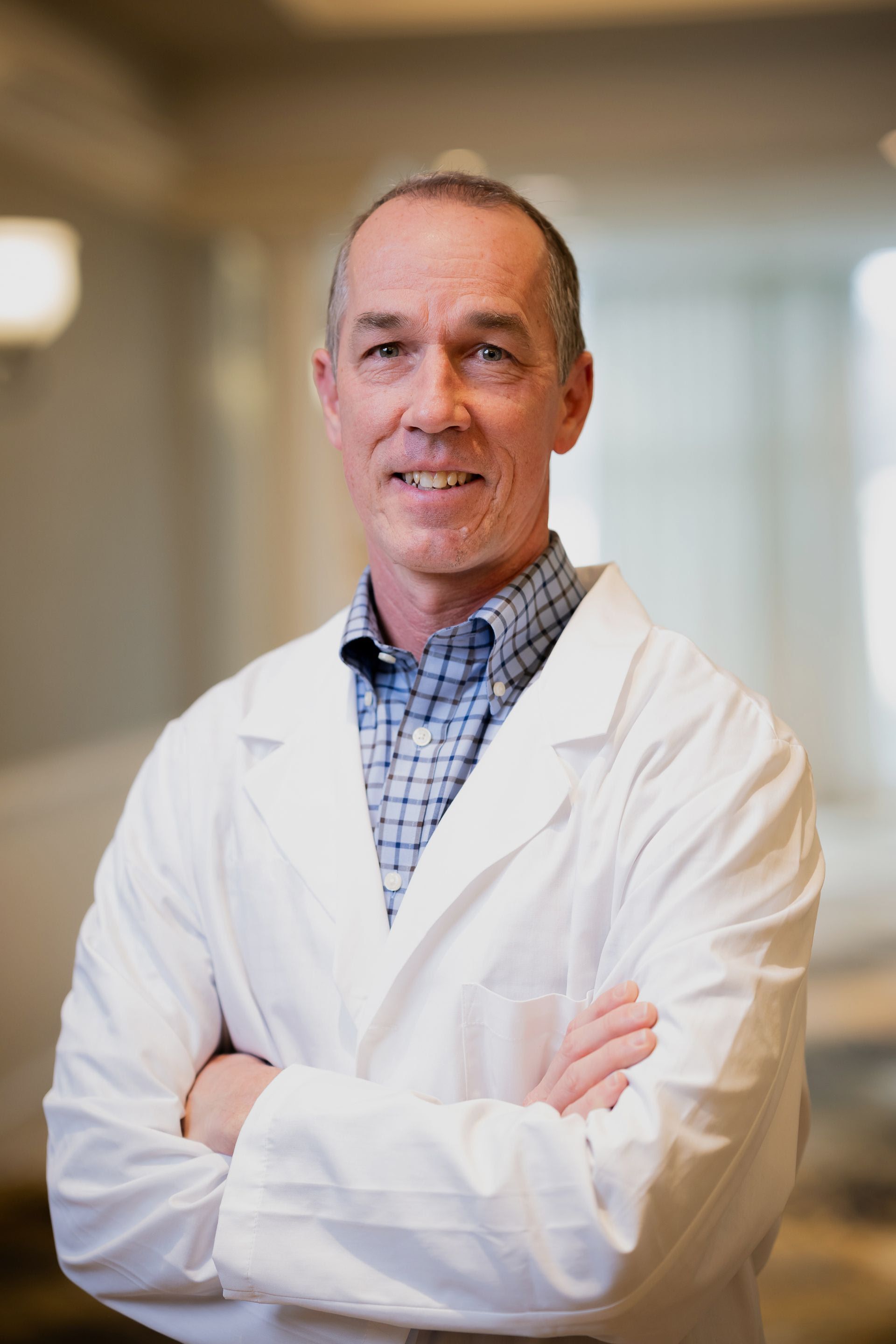 Man in white coat, smiling, in a medical setting.