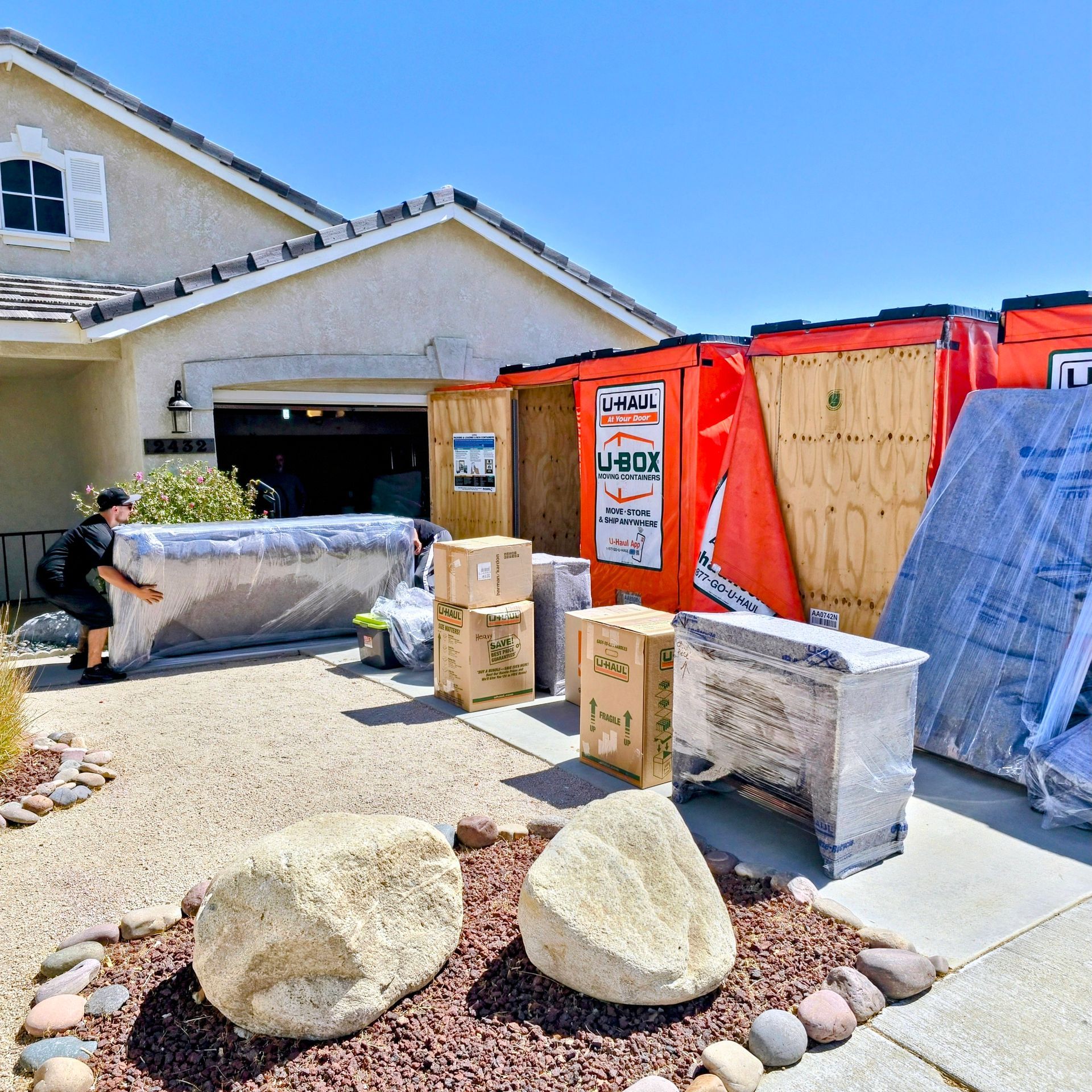 A man is moving a couch in front of a house